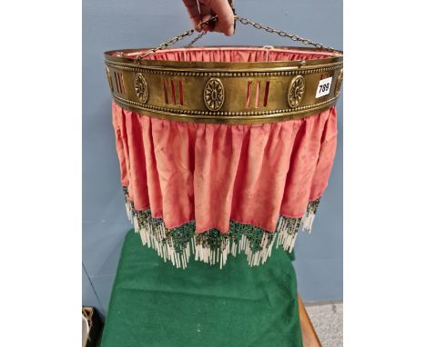 A RED SILK WITH BEADED FRINGE LIGHT SHADE SUSPENDED FROM A BRASS RING AND WITH WEIGHTS TO RAISE AND LOWER THE FITTING, THE BR