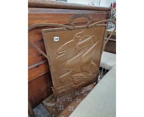 AN ARTS AND CRAFTS FIRESCREEN WITH EMBOSSED COPPER PANEL AND WROUGHT IRON FRAME. 