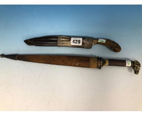A MALAY DAGGER WITH A CARVED HORN HANDLE TO THE BRASS INLAID BLADE, THE HORN SCABBARD WHITE METAL MOUNTED TOGETHER WITH ANOTH