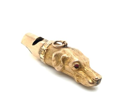 AN ANTIQUE HUNTING DOGS HEAD WHISTLE SET WITH RUBY RED CABOCHON EYES. UNHALLMARKED, ASSESSED AS 9ct GOLD.  LENGTH 4.7cms, WEI