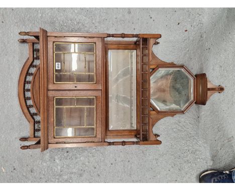 AN ARTS AND CRAFTS OAK WALL CABINET WITH LEADED GLAZED DOORS OVER A BEVELLED MIRRORED BACK BALUSTRADED OPEN SHELF AND A SMALL