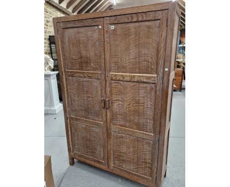 A HEALS OAK WARDROBE WITH PANELLED DOORS ENCLOSING A SHELF ABOVE HANGING SPACE AND A BRASS SHOE RAIL. W 120 x D 40 x H 183.5c