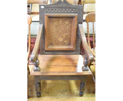 An oak wainscot armchair, the panel back inlaid with a vase of flowers, on turned front legs 