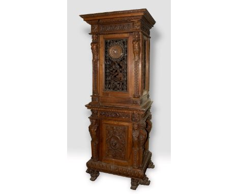 A late 19th/early 20th century walnut cabinet on stand, carved figural caryatids, bell flowers and roundels, the upper sectio