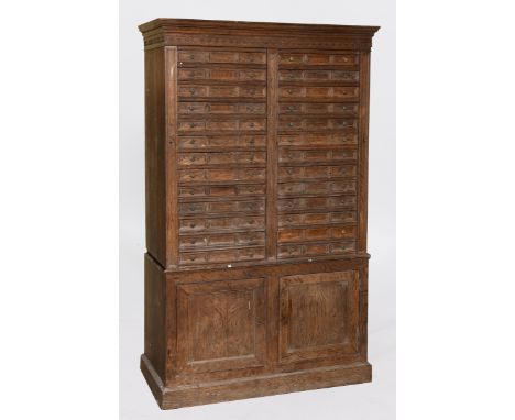 A country house/estate oak Wellington type chest, having two banks of thirteen drawers flanked by lockable sections, above a 