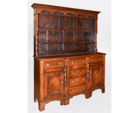 A 19th century oak breakfront dresser, the two tier plate rack above a base with an arrangement of six drawers and a pair of 
