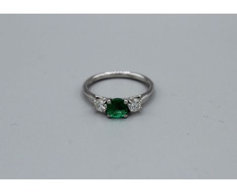 An 18ct white gold vibrant green emerald and diamond trilogy ring. Emerald has an estimated weight of 0.66 carats and has an 