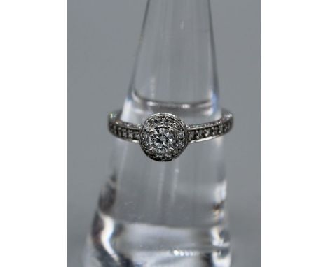 A Bucherer Diamond ring. A white metal and diamond cluster ring, featuring a central diamond of an estimated 0.21 carats, sur