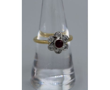 A contemporary 18ct gold and platinum Ruby and diamond daisy ring. Featuring a central dark red ruby with an approximate weig