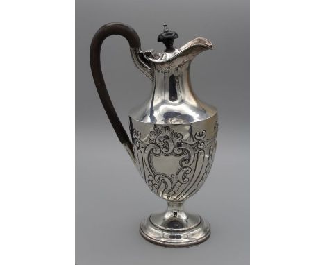 A Victorian Sterling silver footed wine jug, with foliate embossing to the body and with a lid and spout. James Deakin and So