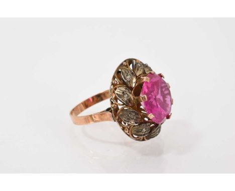 Indian yellow metal cluster ring with a central pink round mixed cut synthetic stone surrounded by diamond set silver leaves 