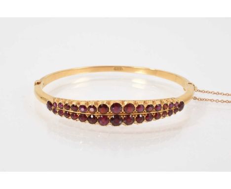 18ct gold and garnet bangle with two rows of graduated round mixed cut garnets in a rub over setting and pierced gallery on a