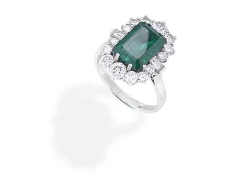 EMERALD AND DIAMOND RINGThe step-cut emerald within a brilliant-cut diamond surround, with baguette-cut diamond shoulders, mo