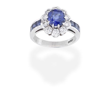 SAPPHIRE AND DIAMOND RINGThe oval-cut sapphire within a scalloped, brilliant-cut diamond surround between step-cut sapphire s