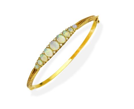 OPAL AND DIAMOND BANGLEThe hinged bangle, set with a graduated row of opal cabochons and cushion-shaped diamonds, mounted in 