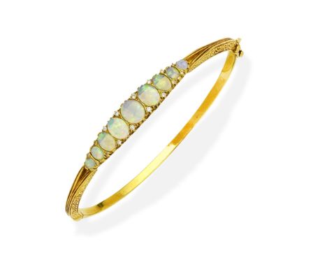 OPAL AND DIAMOND BANGLEThe hinged bangle, set with a graduated row of opal cabochons and cushion-shaped diamonds, mounted in 