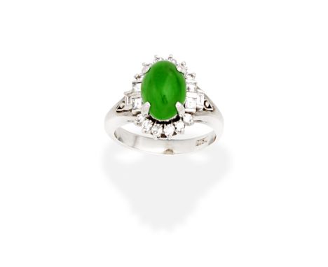 JADE AND DIAMOND RINGThe oval jadeite jade cabochon, within a brilliant-cut diamond surround, between trios of baguette-cut d