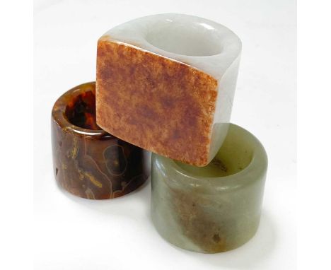 Three Chinese archer's rings,  comprising a mutton fat jade plain example 3.2cm diameter; a jasper example 3cm diameter;and a