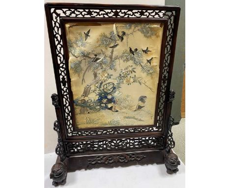 A Chinese carved hardwood fire screen, Qing Dynasty, mid 19th century, the silk embroidered panel finely woven with pheasants