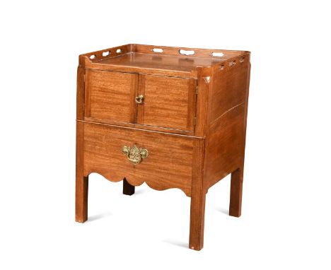 A George III mahogany bedside commode, the pierced tray top over a pair of cupboard doors and a pull out apron raised on squa