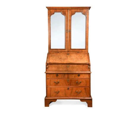A walnut bureau cabinet, early 18th century, the moulded cornice over a pair of arched bevelled mirrored doors above candlesl