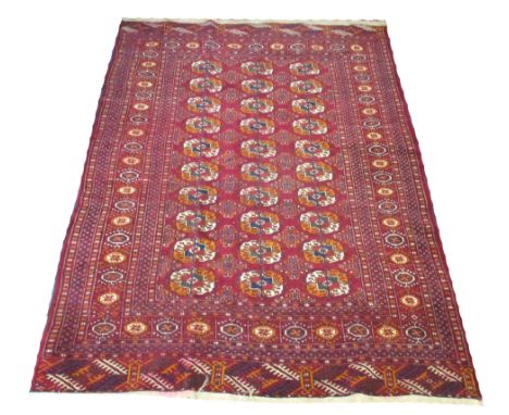 ANTIQUE BOKHARA RUG, 190cm x 130cm, repeat tribal gul motifs on a ruby field within corresponding borders.