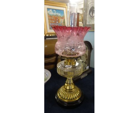 An oil lamp, with clear glass reservoir, brass base and black plinth with cranberry etch glass shade and funnel, maximum heig