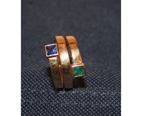 An 18ct gold, emerald and sapphire dress ring, the spiral shank forming three parallel bands to the front and terminating in 