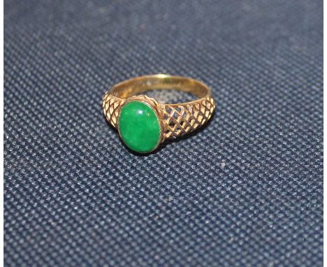 A 14ct. yellow gold and jade ring, set oval apple green jade cabochon to centre with lattice pierced shoulders, shank stamped
