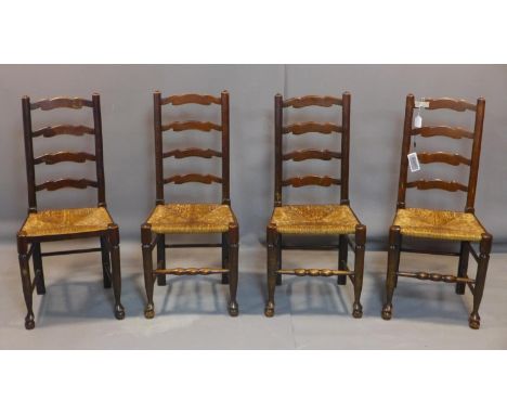 A set of four ladder back dining chairs, with rush seats, on ball feet 