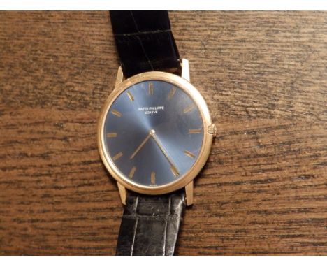 A gent's 18ct gold Patek Philippe automatic wrist watch, the circular blue dial with gold baton numerals, 1.3” diameter on bl