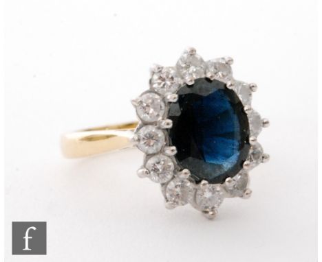 A later 20th Century 18ct hallmarked sapphire and diamond cluster ring, central oval sapphire within a border of twelve brill