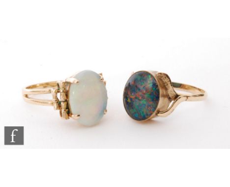 A 14ct single stone opal ring, oval claw set stone to a split shank, with a similar opal doublet ring. (2) 