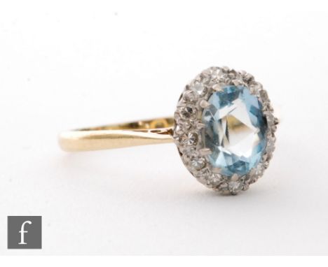 An 18ct aquamarine and diamond cluster ring, central oval aquamarine within a diamond set border, ring size T 1/2. 