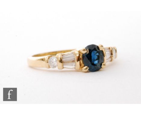 A modern 18ct hallmarked sapphire and diamond ring, central claw set sapphire flanked by two tapering baguettes and a brillia