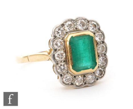 An 18ct hallmarked emerald and diamond cluster ring, central collar set emerald cut emerald within a fourteen stone diamond s