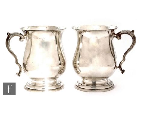 A pair of hallmarked silver baluster tankards of plain form terminating in acanthus leaf capped scroll handles, height 12cm, 