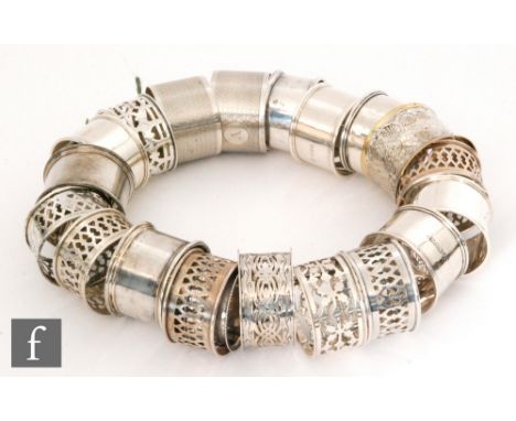 Nineteen hallmarked silver circular napkin rings to include engine turned and pierced examples, total weight 11.5oz, with a s