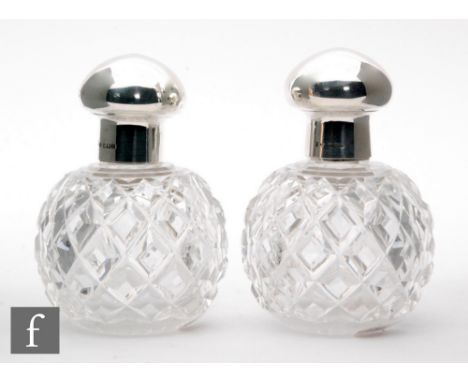 A pair of hallmarked silver and clear glass scent bottles, diamond cut glass bodies below plain silver collars and covers, he