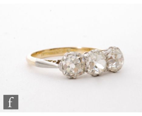 An 18ct three stone diamond ring, claw set cushioned old cut stones to knife edged shoulders, ring size J 1/2. 