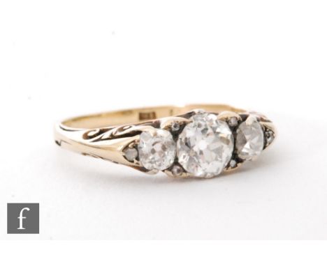 A late 19th Century 18ct diamond three stone ring, old cut stones spaced with further diamond chips, centre stone approximate