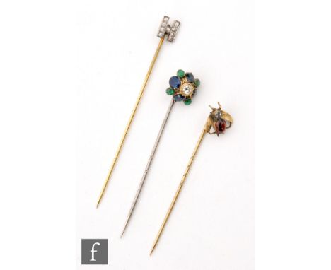 Three early 20th Century stick pins, a diamond and garnet set bug, an initial H and a sapphire emerald and diamond set exampl