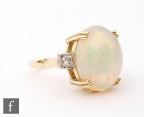 An 18ct opal and diamond three stone ring, central oval cabochon cut claw set opal flanked by a brilliant cut diamond to eith