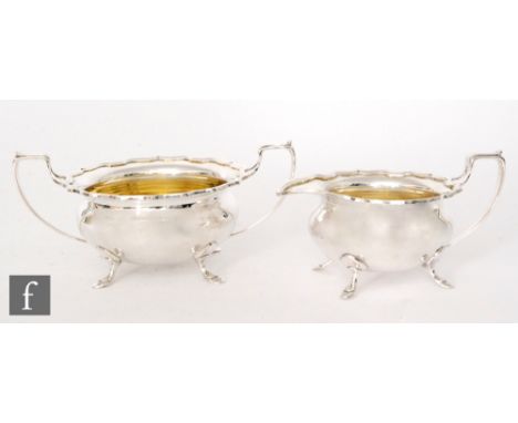 A hallmarked silver cream jug and sugar basin each raised on four pad feet below waved borders and scrolled handles, total we