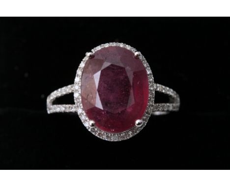 A 14k white gold and diamond ring set with an oval cut ruby approx. 5.30ct Diamonds approx. 0.40 total weight