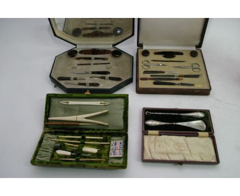 A cased antique ivory manicure set, two later cased sets and a steel shoehorn and button hook set 