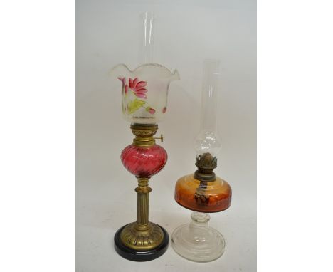 A Victorian oil lamp with cranberry glass reservoir, painted shade and chimney plus another oil lamp with coloured glass rese