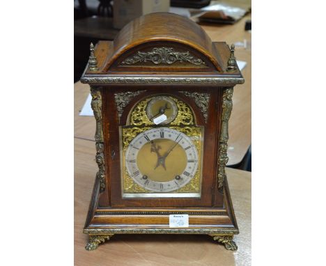 A large Edwardian oak bracket clock with gilt metal mounts, double cylinder movement striking on gongs with later bracket and