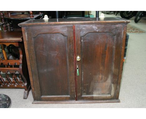 An oak hanging cabinet with a pair of double doors enclosing a single shelf