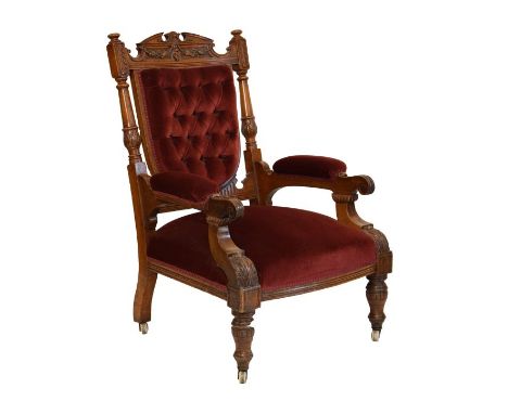 Late Victorian carved oak framed library armchair, the broken-arched back carved with panels of fruit over deep-buttoned shie